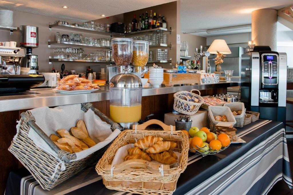 a counter with baskets of bread and baskets of orange juice at Hôtel L&#39;Océane in Andernos-les-Bains