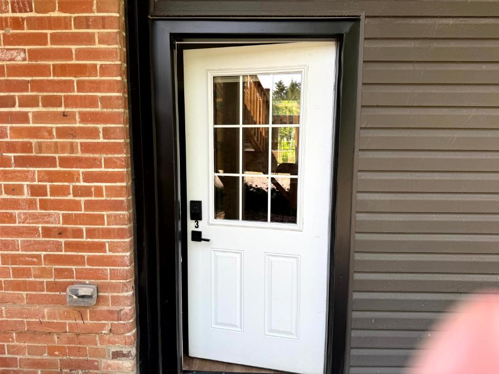 a white door with a window on a brick building at Burk's Fall River View 2b2b in Burks Falls