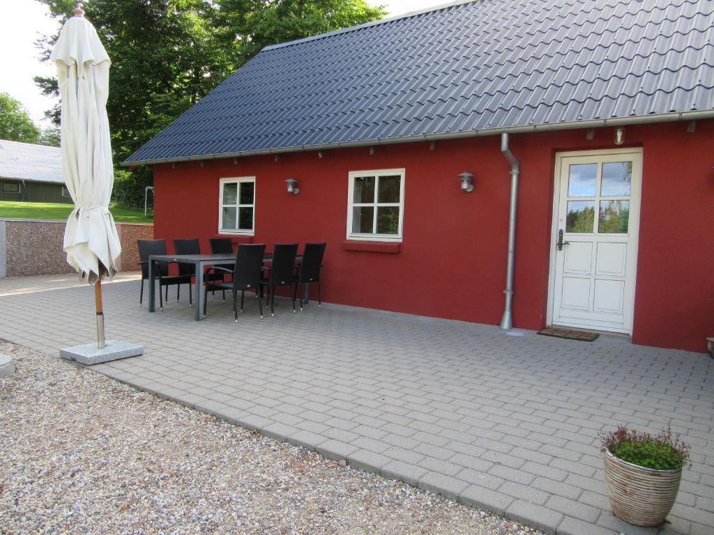 a red building with a table and chairs and an umbrella at Hedelodden Apartment in Uve