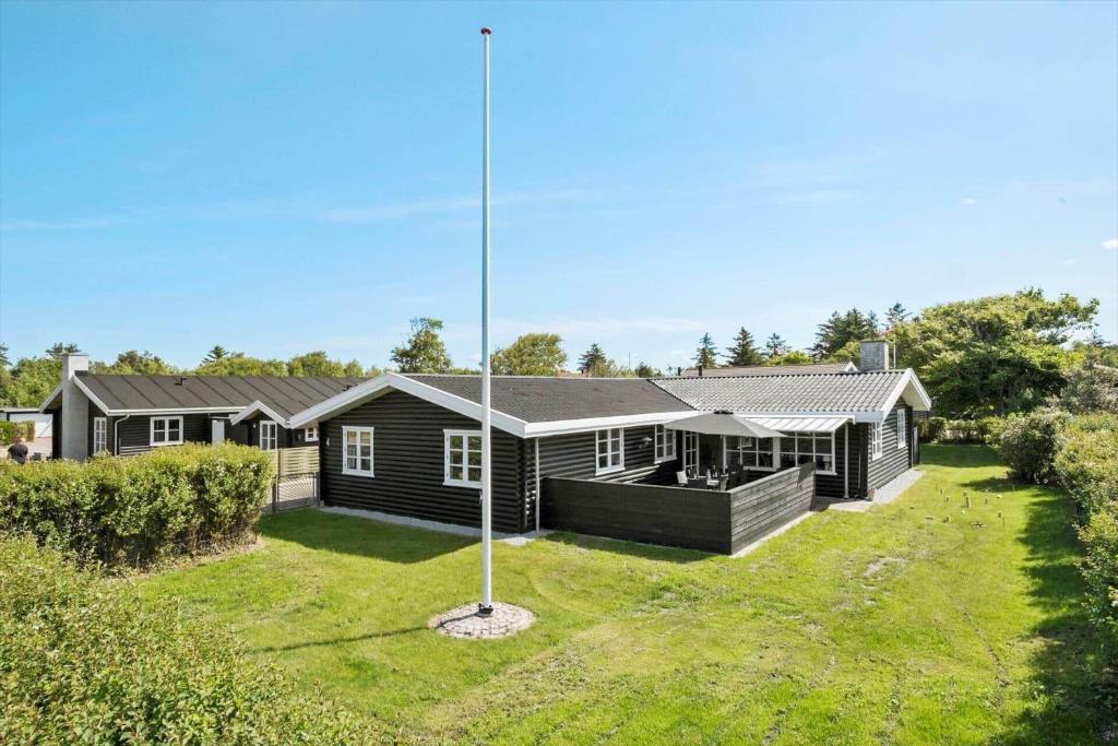 una casa con un'asta della bandiera nel cortile di BL1284-Blokhus-Tyttebaervej-4 a Blokhus