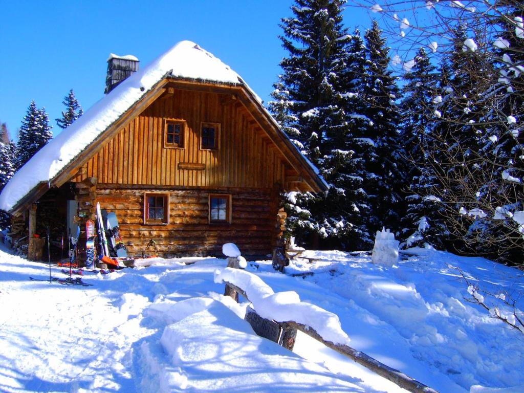 eine Blockhütte im Schnee mit schneebedeckten Bäumen in der Unterkunft Bischofhütten in Bad Sankt Leonhard im Lavanttal
