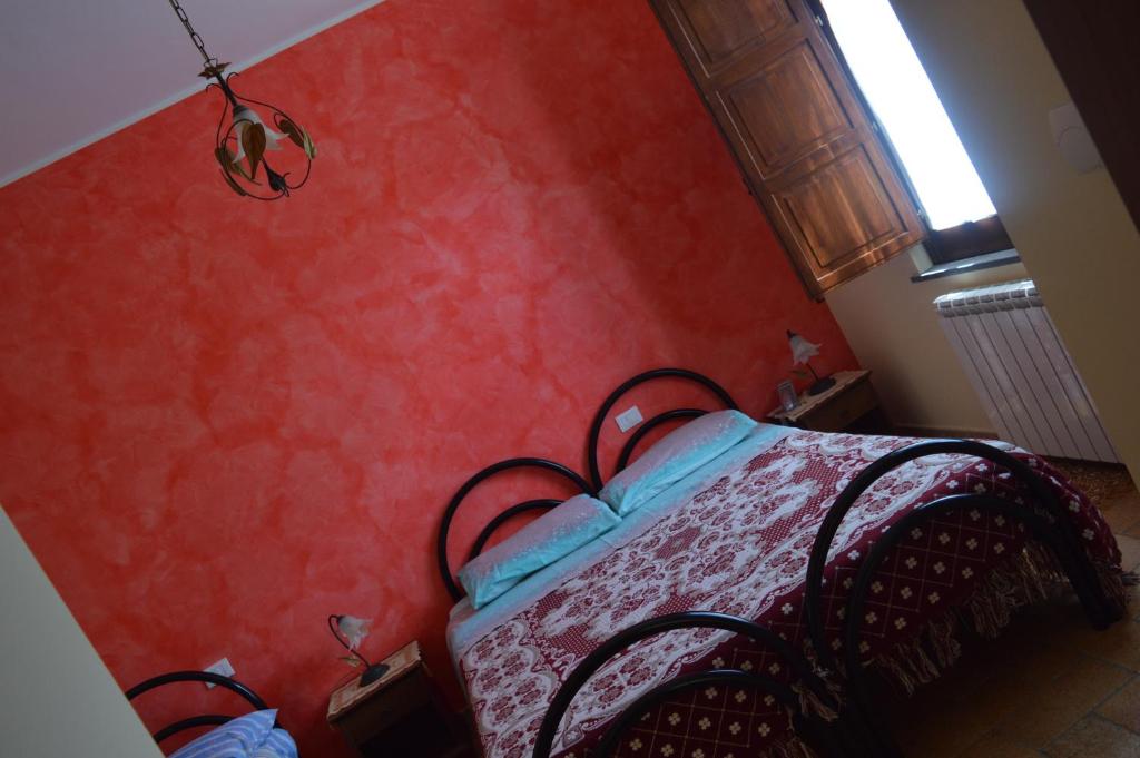 sypialnia z łóżkiem z czerwoną ścianą w obiekcie Agriturismo E Turre w mieście Serrastretta