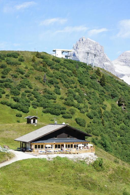 a house on a hill with a mountain in the background at Berggasthaus Edelweisshütte Ladurns in Fleres