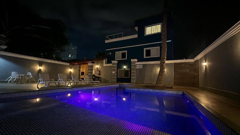 a swimming pool at night with a house at Marmeu Enseada in Guarujá