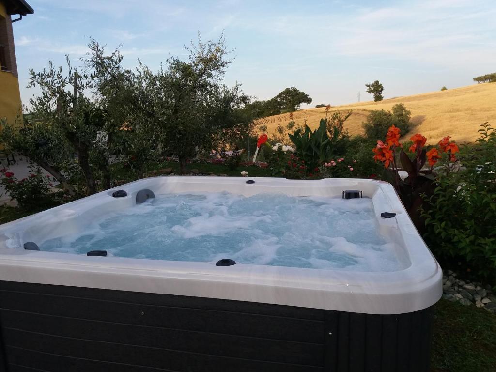 a hot tub in a yard with flowers at Agriturismo La Stradaccia in Ginestreto