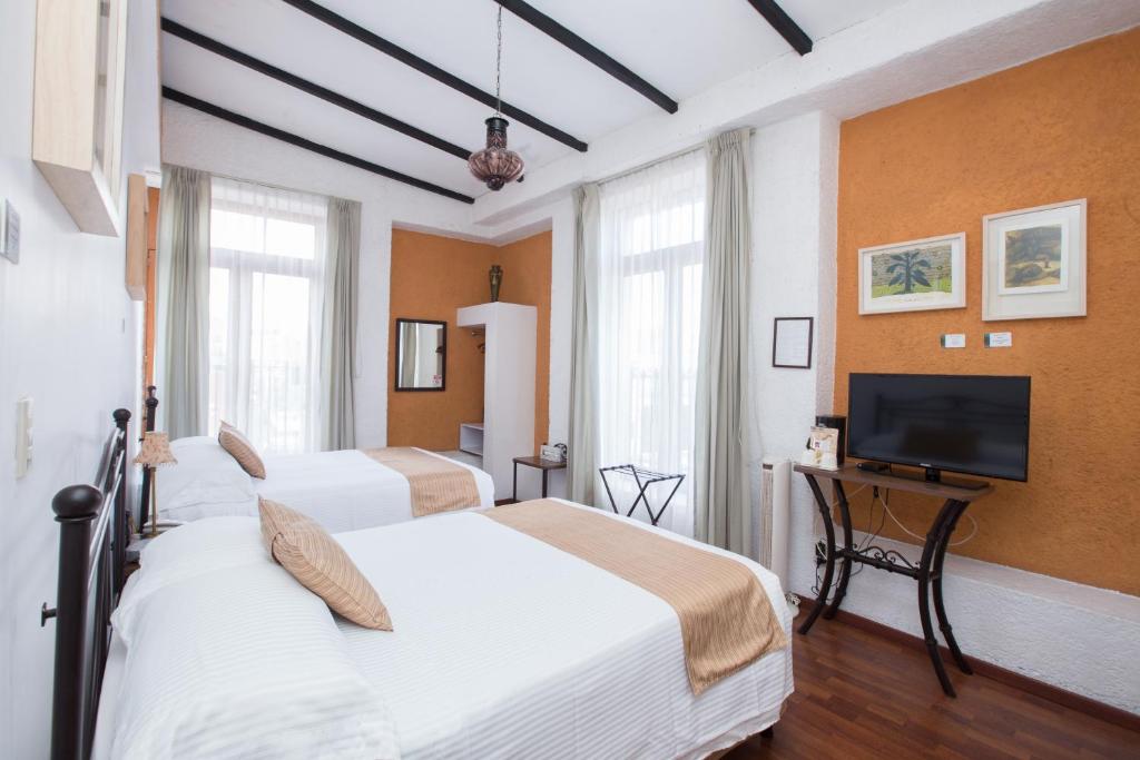 a hotel room with three beds and a flat screen tv at Hotel Pórtico Cultural in Morelia