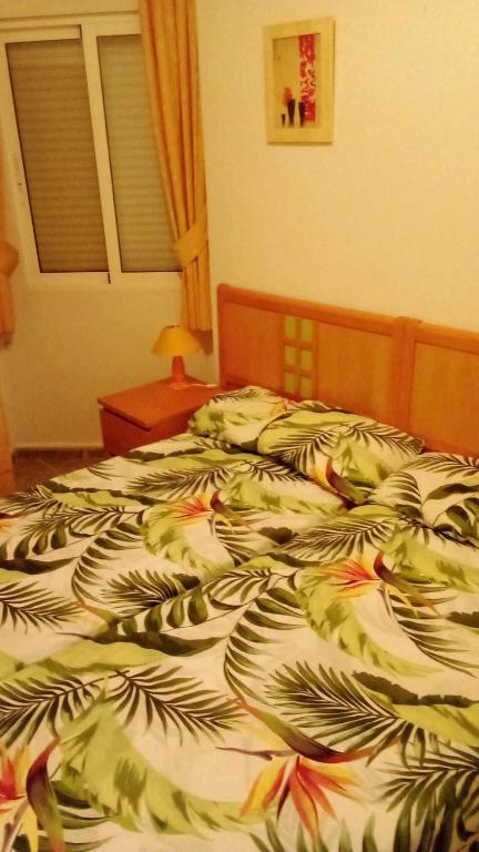 un letto in una camera da letto con un piumone con foglie di Stephen a Torrevieja