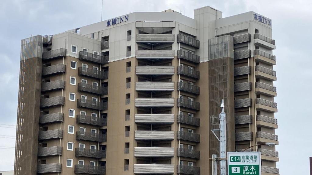 Un edificio alto con un cartel delante. en Toyoko Inn Nishi Funabashi Baraki Inter, en Ichikawa