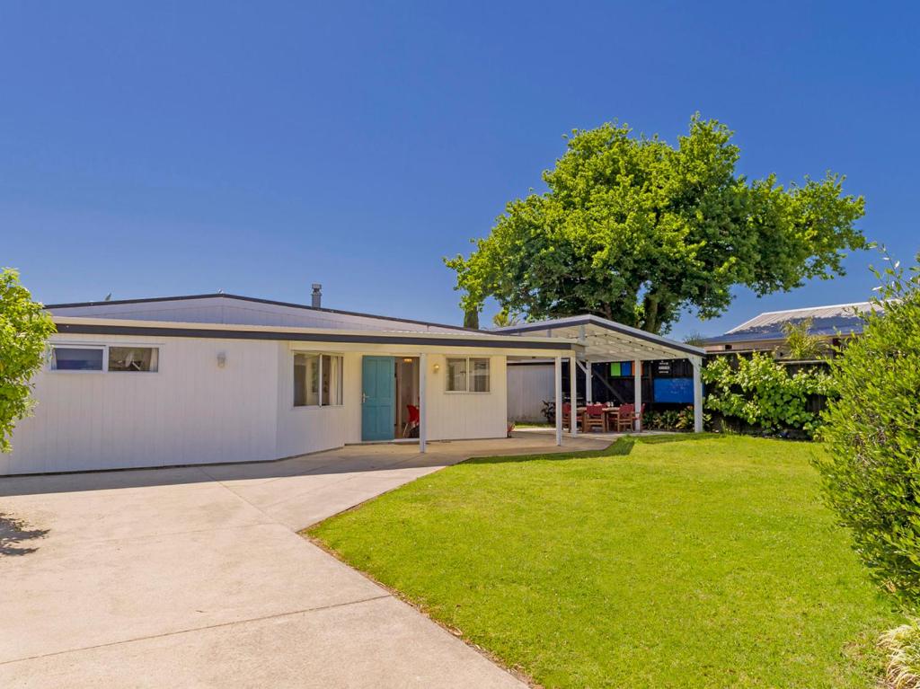a large white house with a grass yard at Gone Coastal - Whangamata Holiday House in Whangamata
