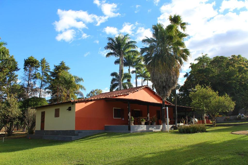 Casa roja y blanca con palmeras en A Sua Casa de Campo na Chapada, en Alto Paraíso de Goiás