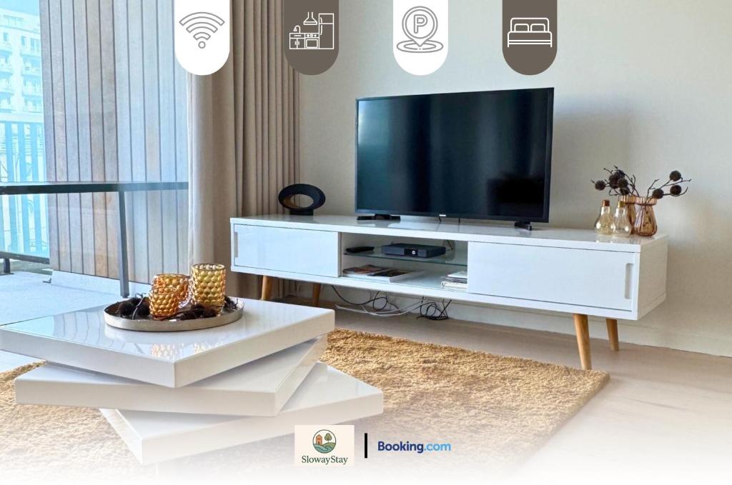 a living room with a television on a white entertainment center at Sea View 1 BR Flat With Pool - Ideal For Couples & Families By SlowayStay Holiday Apartment & Short Term Rental Oostende in Ostend