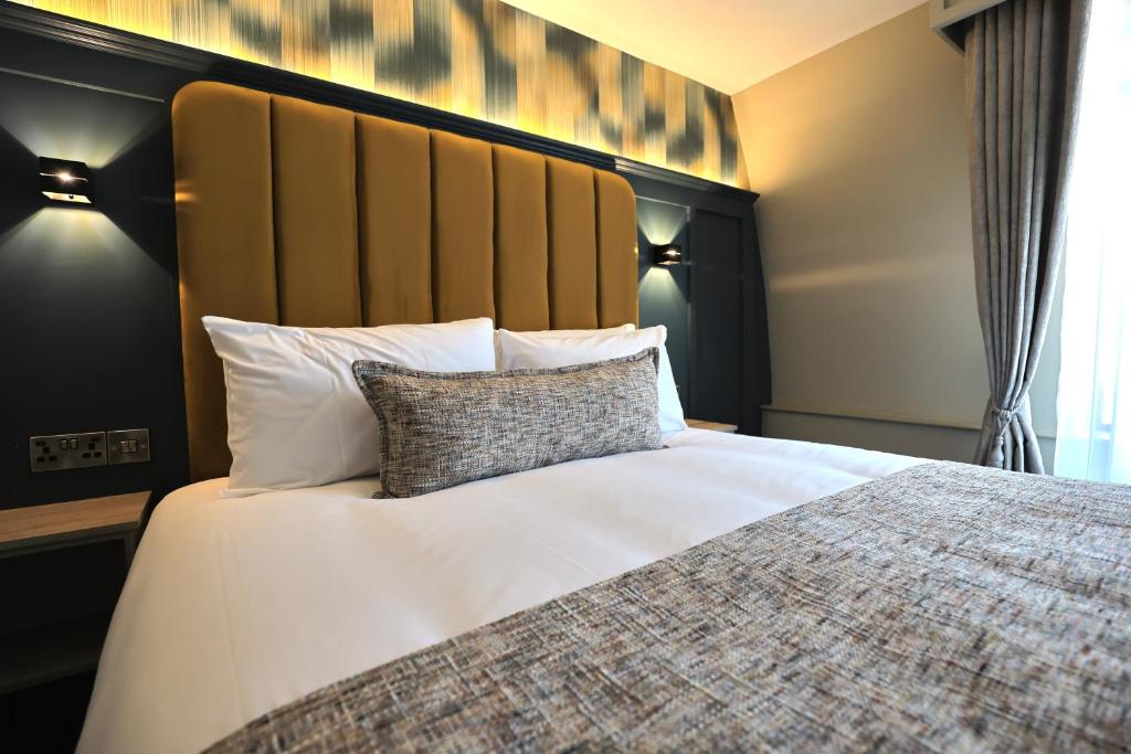 a bedroom with a large bed with white sheets and pillows at The Maiden City Hotel in Derry Londonderry