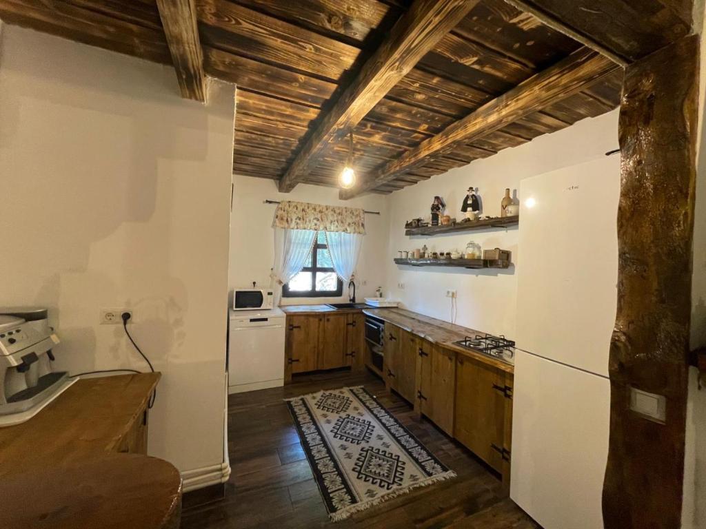 a kitchen with white appliances and wooden ceilings at Casuța cu târnaț in Colibiţa