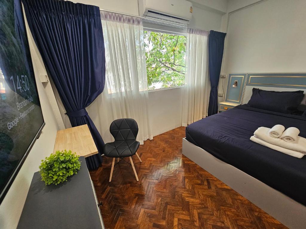 Un dormitorio con una cama y una silla y una ventana. en Middletown chiangmai 2king bed, en Chiang Mai