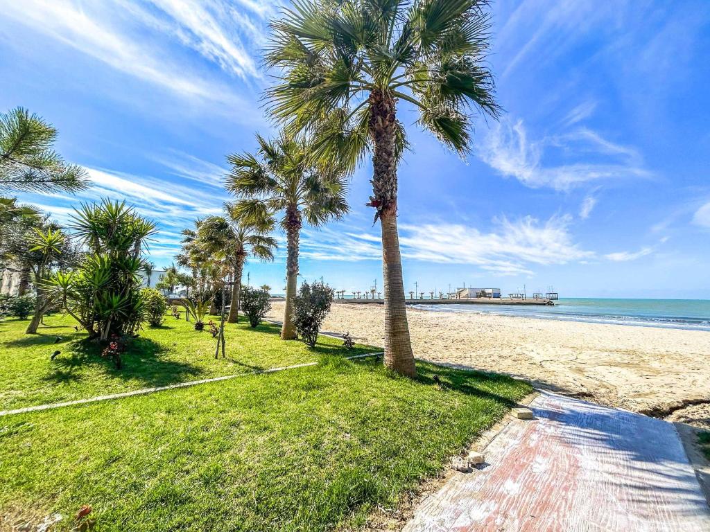 a sandy beach with palm trees and the ocean at Marine Center in Golem