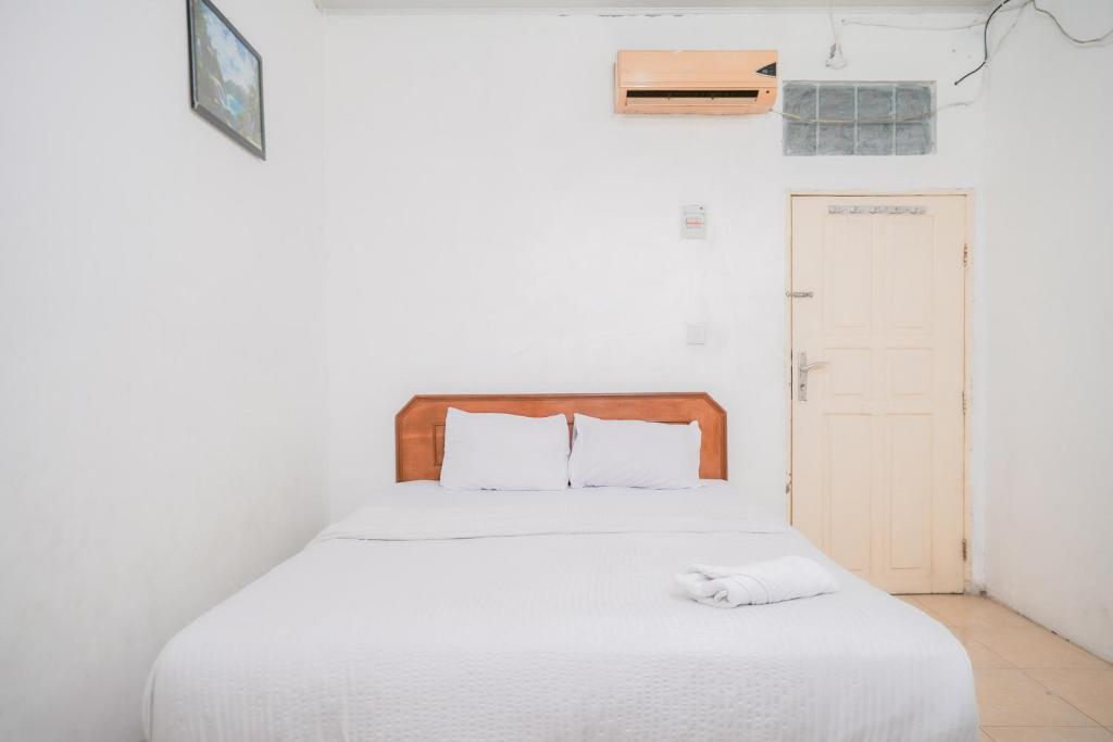 a white bed with a white towel on top of it at Urbanview Hotel Mine Residence Syariah in Padang