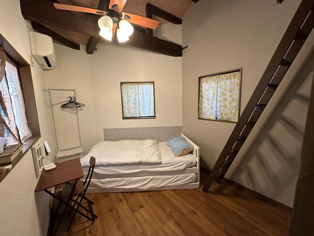 a small room with a bed and a staircase at Ryokoheya Awajikan in Osaka