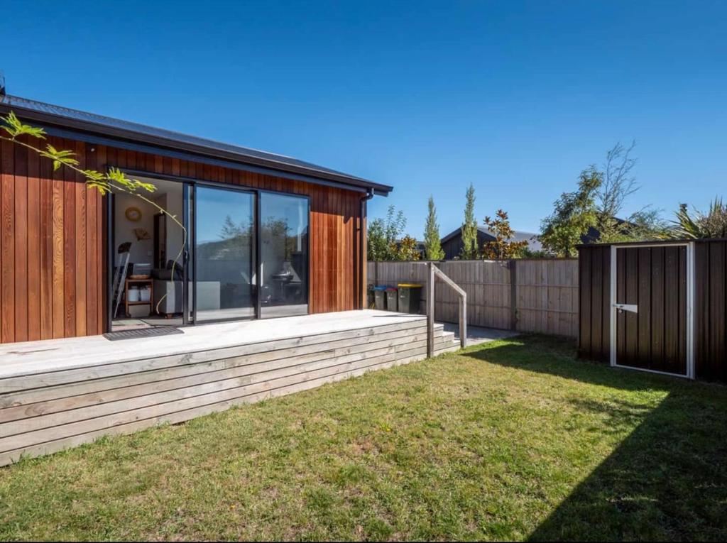 Queenstown AirportにあるMeraki Guesthouseのガラスの壁とフェンスのある家
