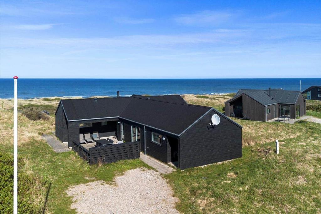 a black house on the beach near the ocean at LK1463-Lokken-Rosavej-11 in Løkken