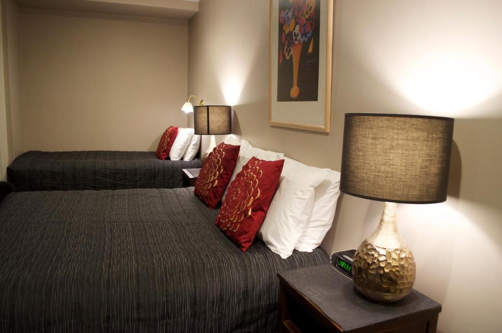Pokój hotelowy z łóżkiem z białymi i czerwonymi poduszkami w obiekcie Diplomat Motel w mieście Christchurch