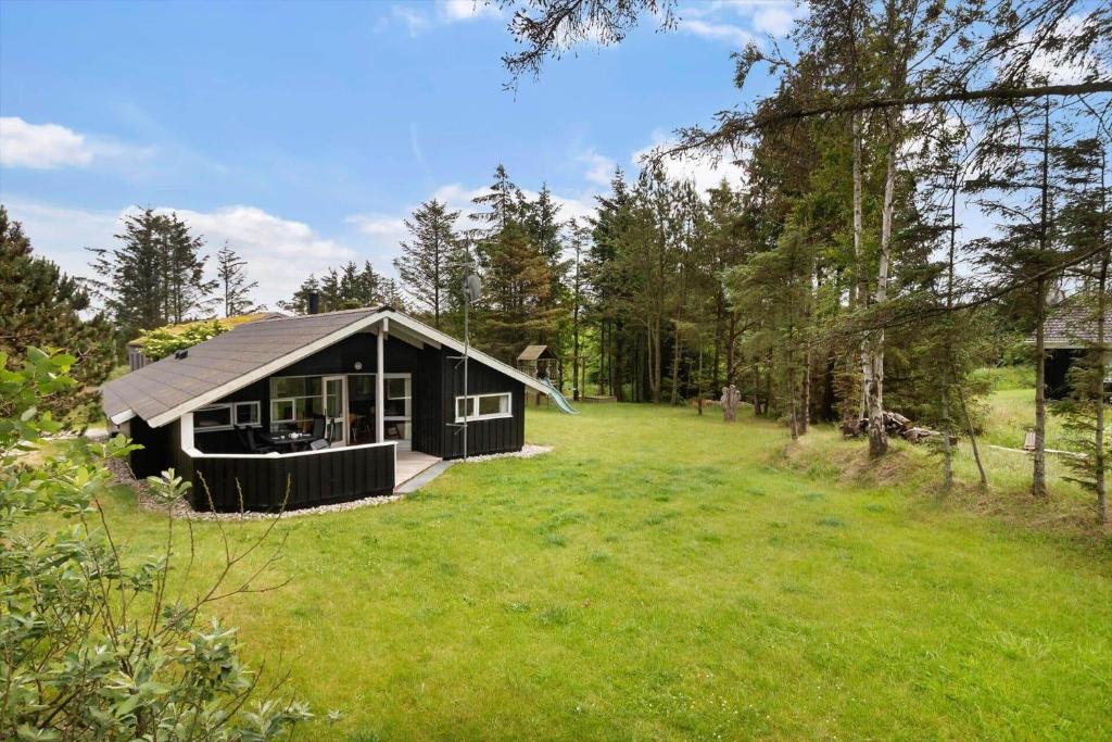 a black cabin in the middle of a grass field at LK599-Lokken-Stellavej-16 in Løkken