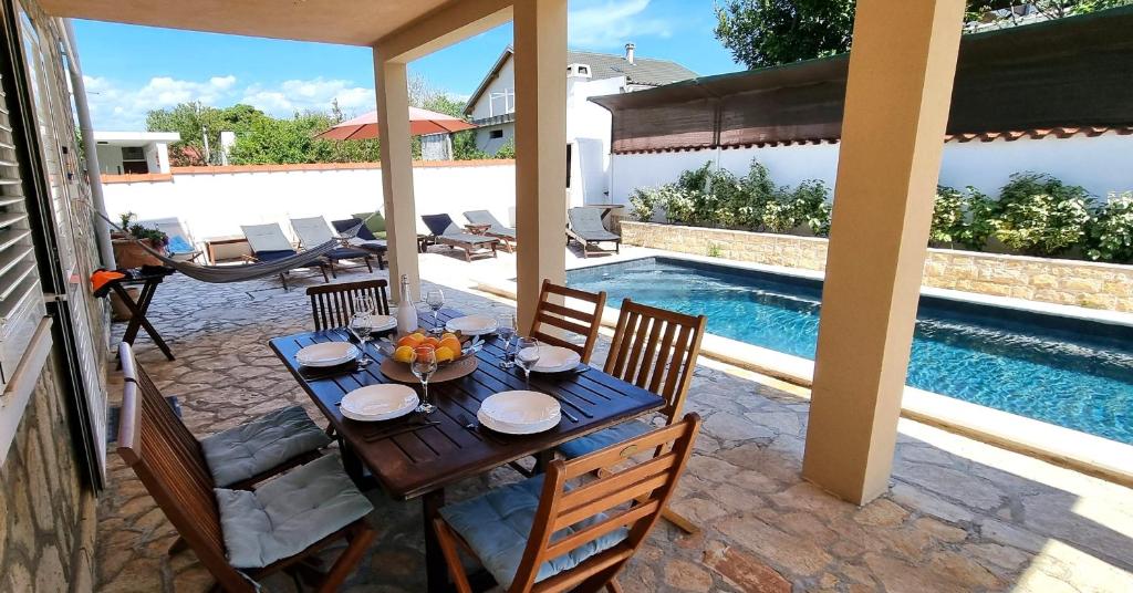 een houten tafel met stoelen naast een zwembad bij Apartment 5237-1 in Batalaži