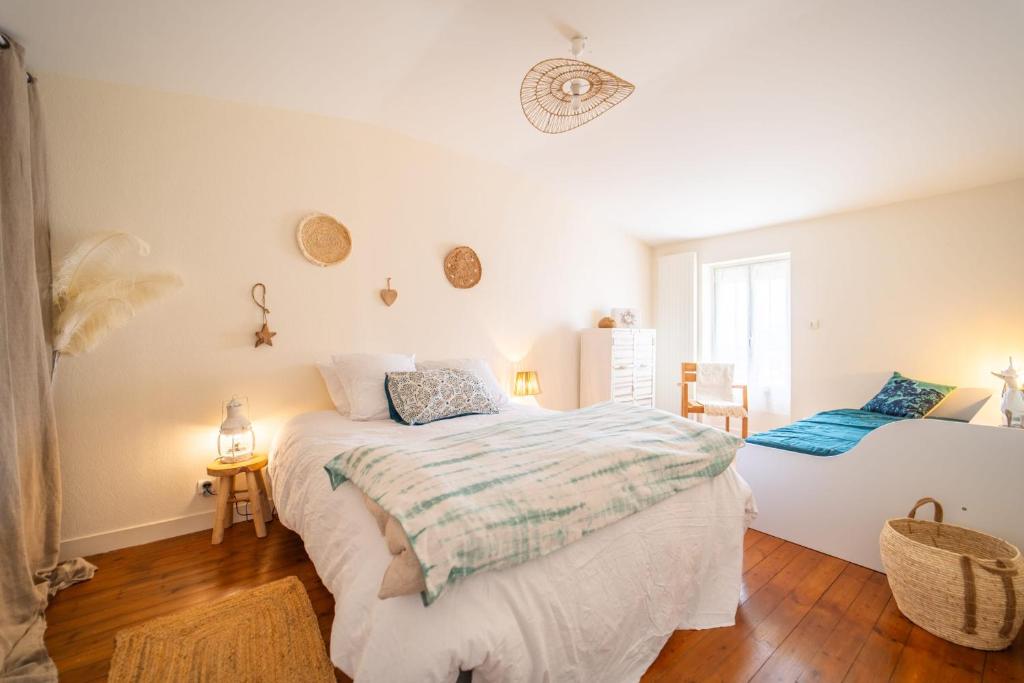 a white bedroom with a bed and a chair at Maison au cœur de la Chaume Garage fermé in Les Sables-dʼOlonne