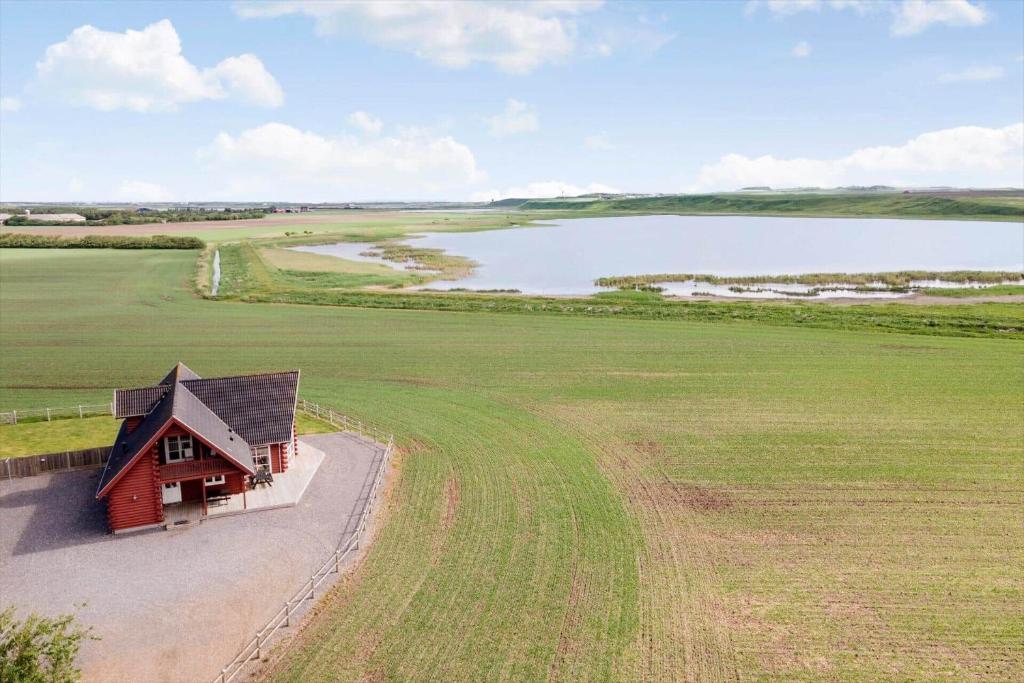 a small red building in a field next to a lake at 289-Harboore-Strandvejen-179 in Harboør