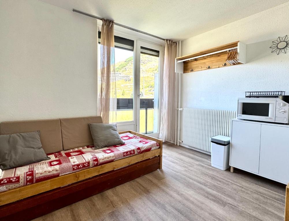 Una pequeña habitación con una cama y un microondas. en Cosy Studio ski-in ski-out, au coeur des Menuires, en Les Menuires