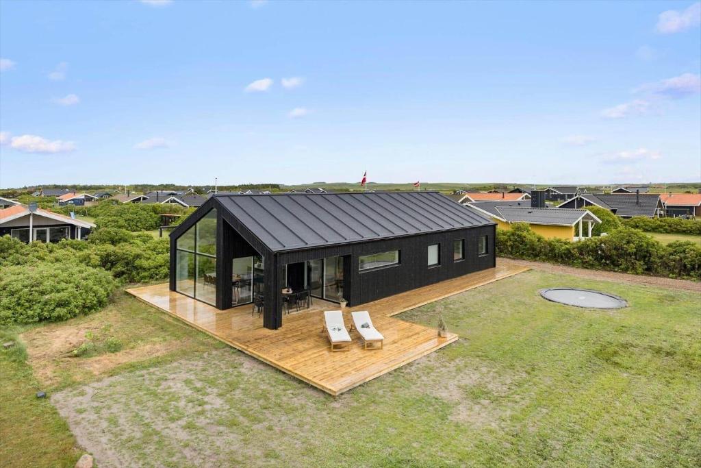 una casa negra con dos sillas blancas en una terraza en 279-Harboore-Neerlandiavej-72, en Harboør