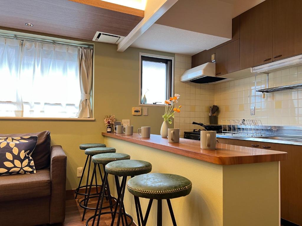 Una cocina con una barra con taburetes y un sofá. en nestay apartment tokyo akihabara, en Tokio