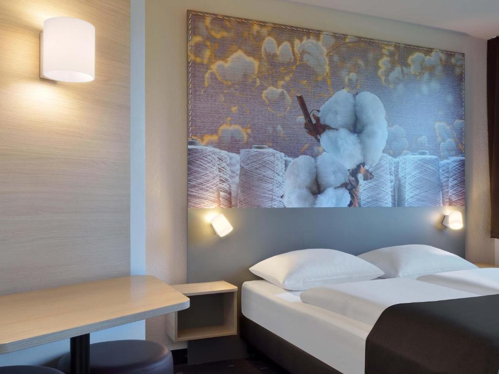 ラーティンゲンにあるB&amp;B Hotel Düsseldorf-Ratingenのベッドと壁に絵が飾られたホテルの部屋