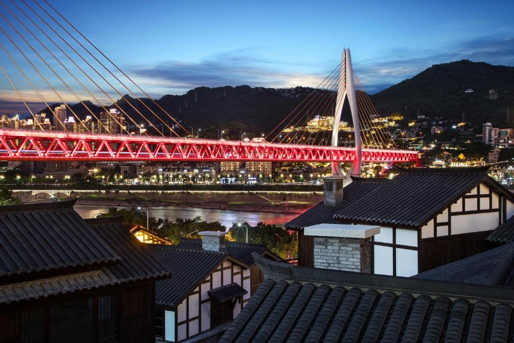 a red bridge over a river with a city at 重庆山南雨江景别墅酒店 in Chongqing