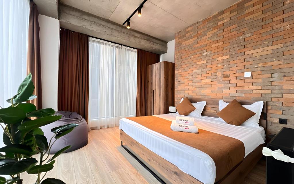 Un dormitorio con una cama con una pared de ladrillos. en Rooms Apart Hotel by RED, en Ereván