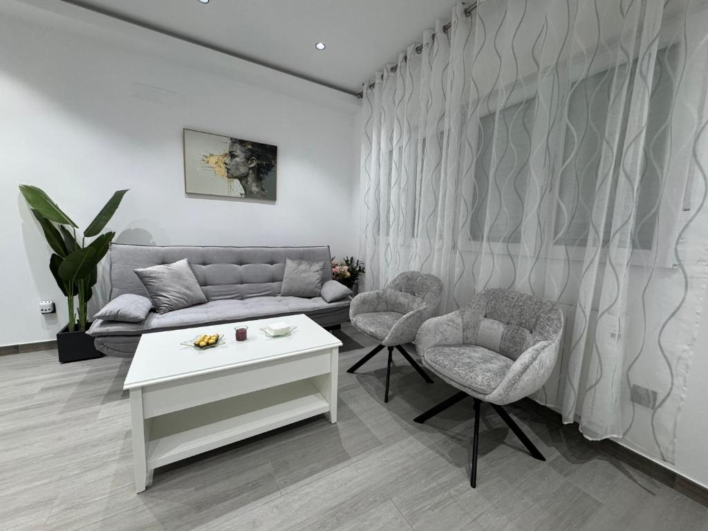 un salon avec un canapé et deux chaises dans l'établissement Apartamento AEROPUERTO12, à Coslada
