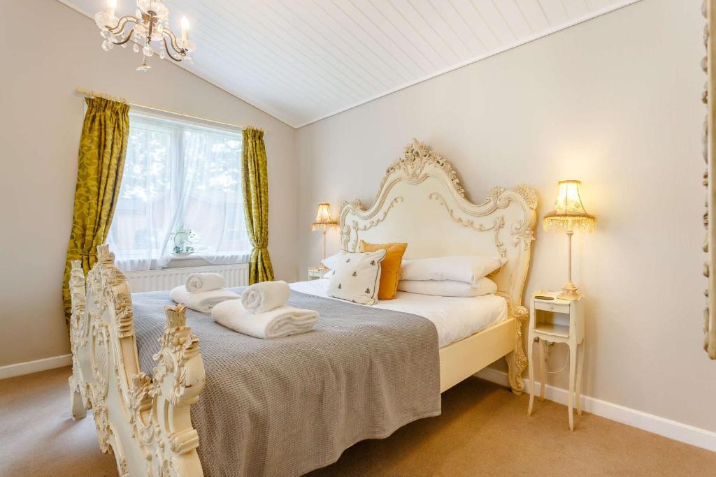 Un dormitorio con una cama blanca y una ventana. en Romeo Lodge, en Kingham