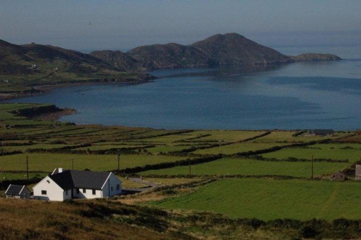 a house on a hill next to a large body of water at Skellig Bay Cottage in Waterville