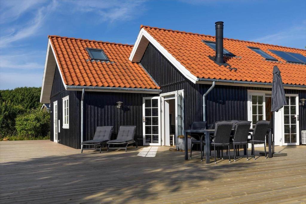 a black house with chairs and an orange roof at 16632-Farevejle-Karuphoj-4-C in Fårevejle