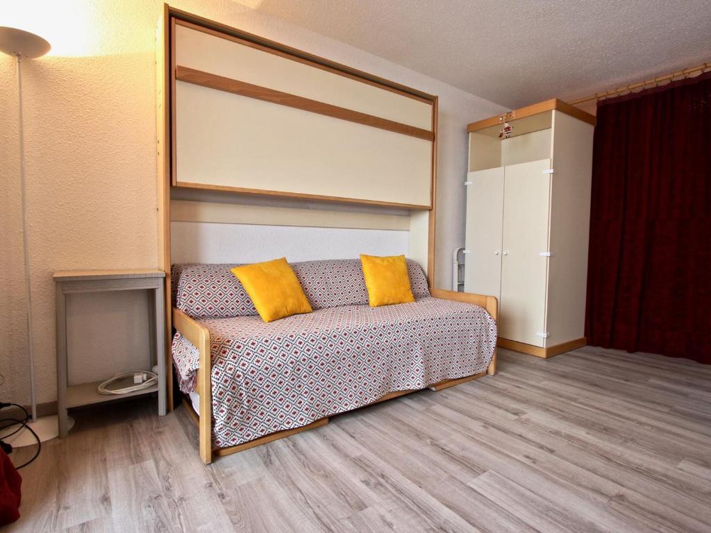 una camera da letto con un letto con cuscini gialli di Studio rénové 2018 avec parking couvert et animaux admis - FR-1-340-128 a Chamrousse