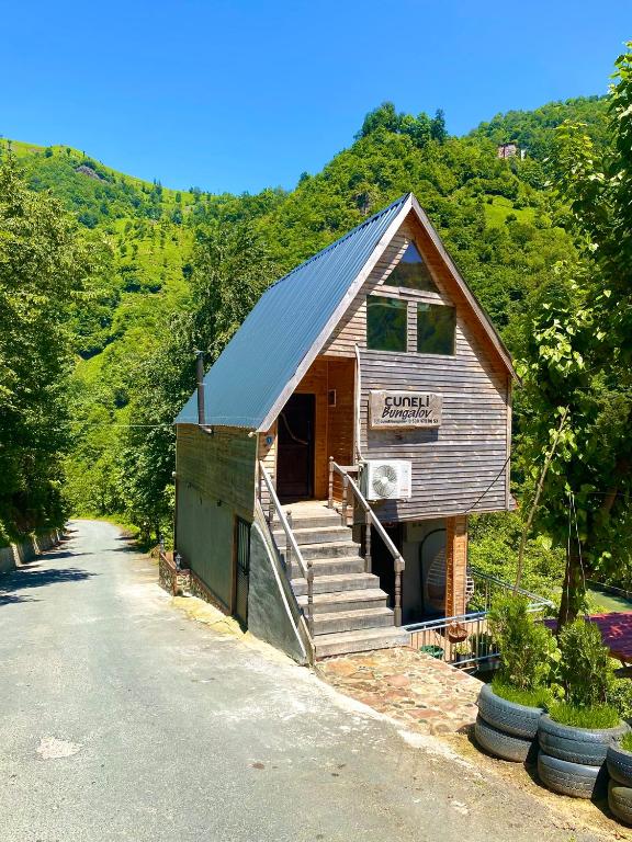 a small building with stairs next to a road at Cuneli bungalov in Çamlıhemşin