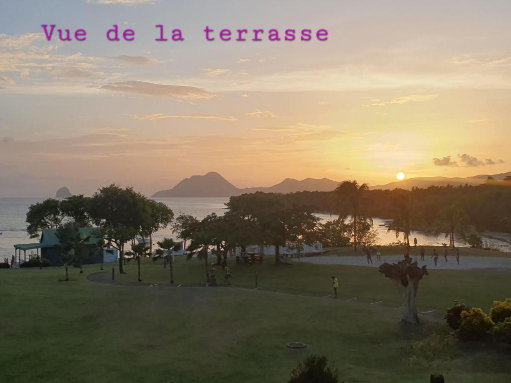 a sunset over a park with the words we do la franchise at T3 Rhum Passion vue mer et rocher du Diamant dans célèbre Village de Vacances in Sainte-Luce