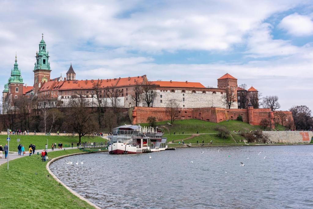 ein Boot im Wasser vor einem großen Schloss in der Unterkunft Old Town Stage The Studio Suite Quartet in Krakau