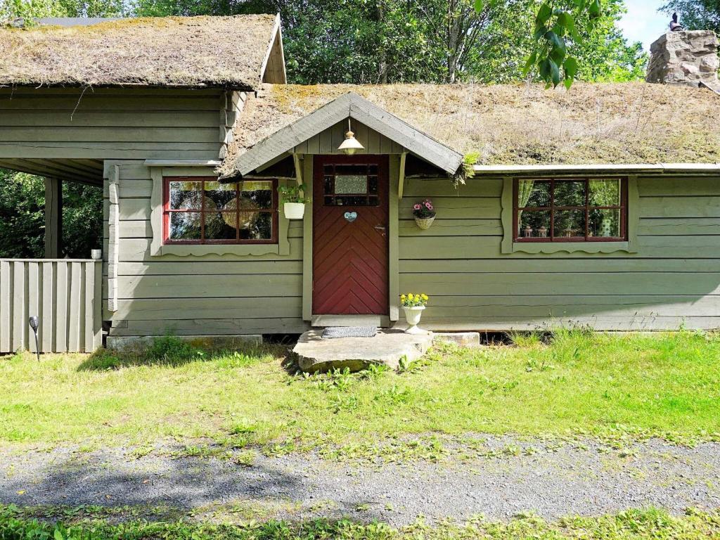a small green house with a red door at 5 person holiday home in Tingsryd in Tingsryd