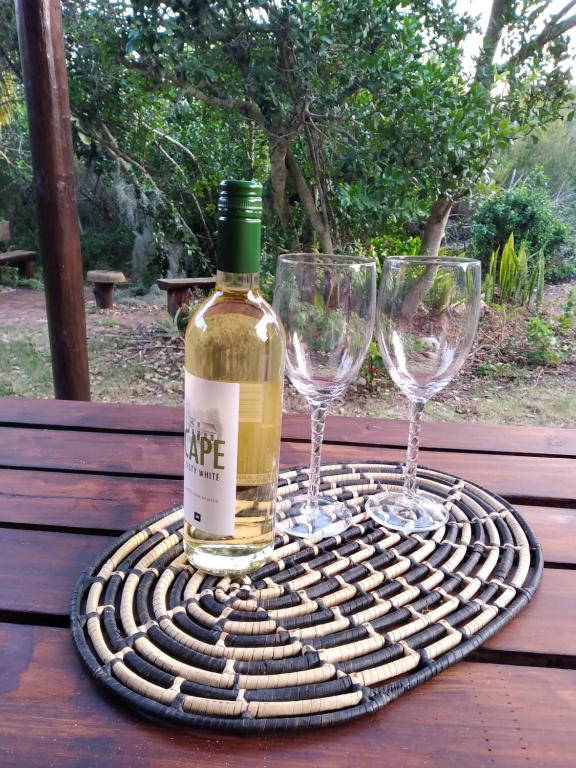 Una botella de vino y dos copas de vino en una mesa en Bush Beach Safari Accommodation, en Jeffreys Bay