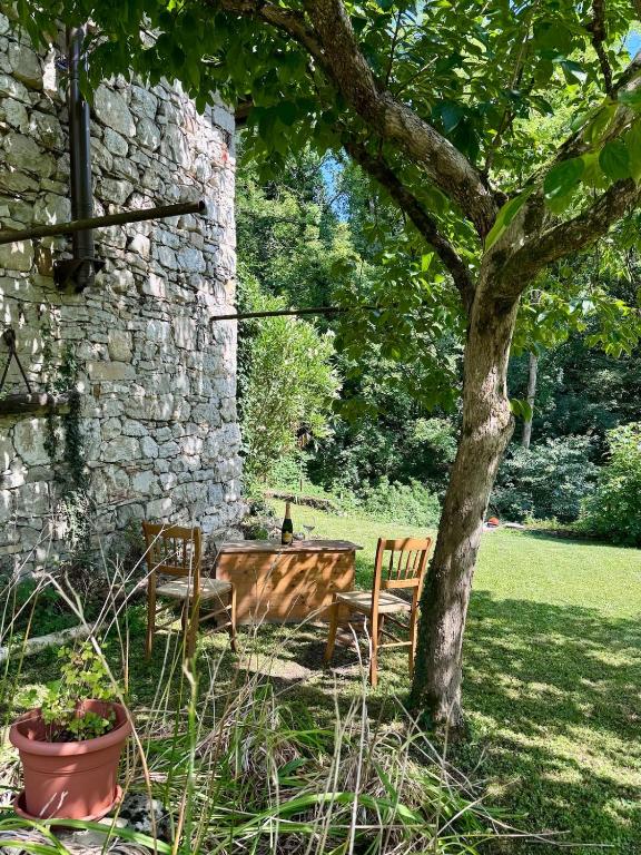 a table and chairs under a tree next to a stone wall at Casa del Sorriso in Costa