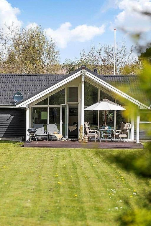 a house with a patio with chairs and an umbrella at 1572-Melby-Kildegardsvej-10 in Melby