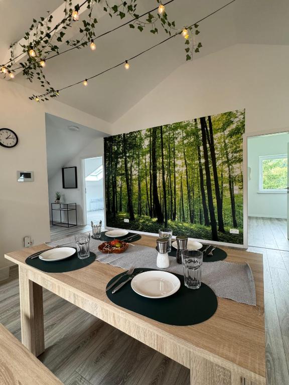 a dining room with a table with plates and glasses at Waldzauber - Moderne Ferienwohnung im Grünen in Elpenrod