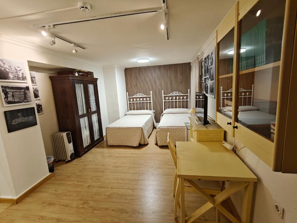 ein Zimmer mit zwei Betten und einem Tisch und einem Schreibtisch in der Unterkunft Alojamiento la Casa del Brigadier in Cerro Muriano