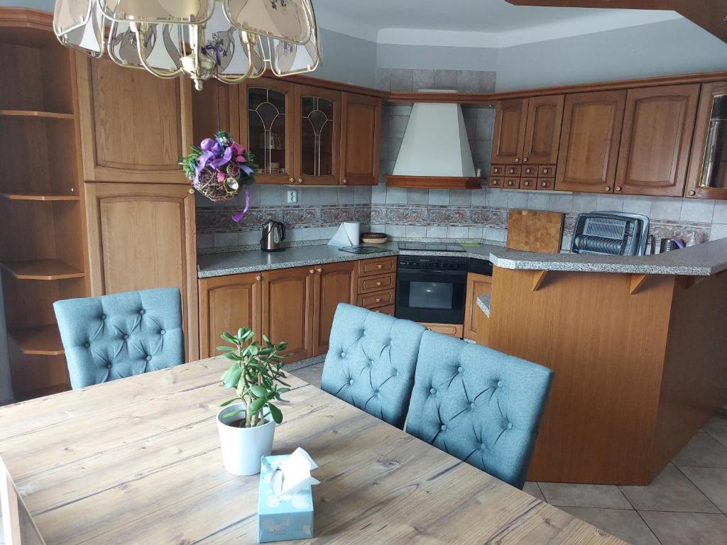 a kitchen with a wooden table and blue chairs at Apartmán Rainbow se zahradou, bazénem a parkováním in Karlovy Vary