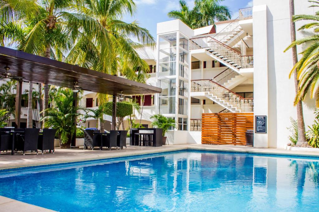 a swimming pool in front of a building with palm trees at Hotel Plaza Inn in Los Mochis